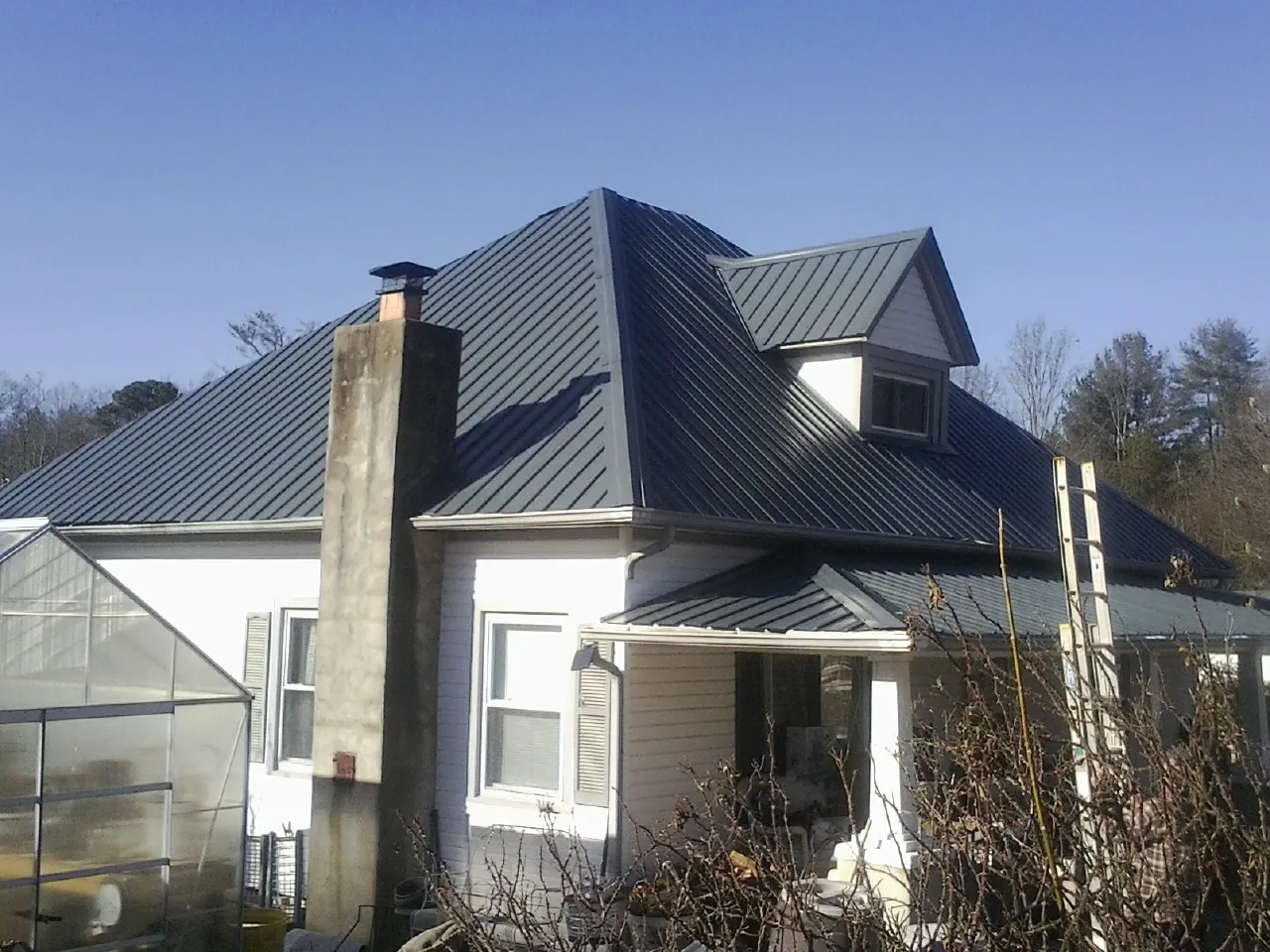 Dark blue standing seam metal roof on a white farmhouse with dormer — Slate & Tile Roof Repair by Roofing Brothers in Idleyld Park
