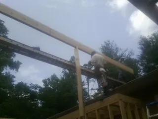 Carpenter setting a ridge beam over a new addition frame — Ice Dam Removal by Roofing Brothers in Idleyld Park