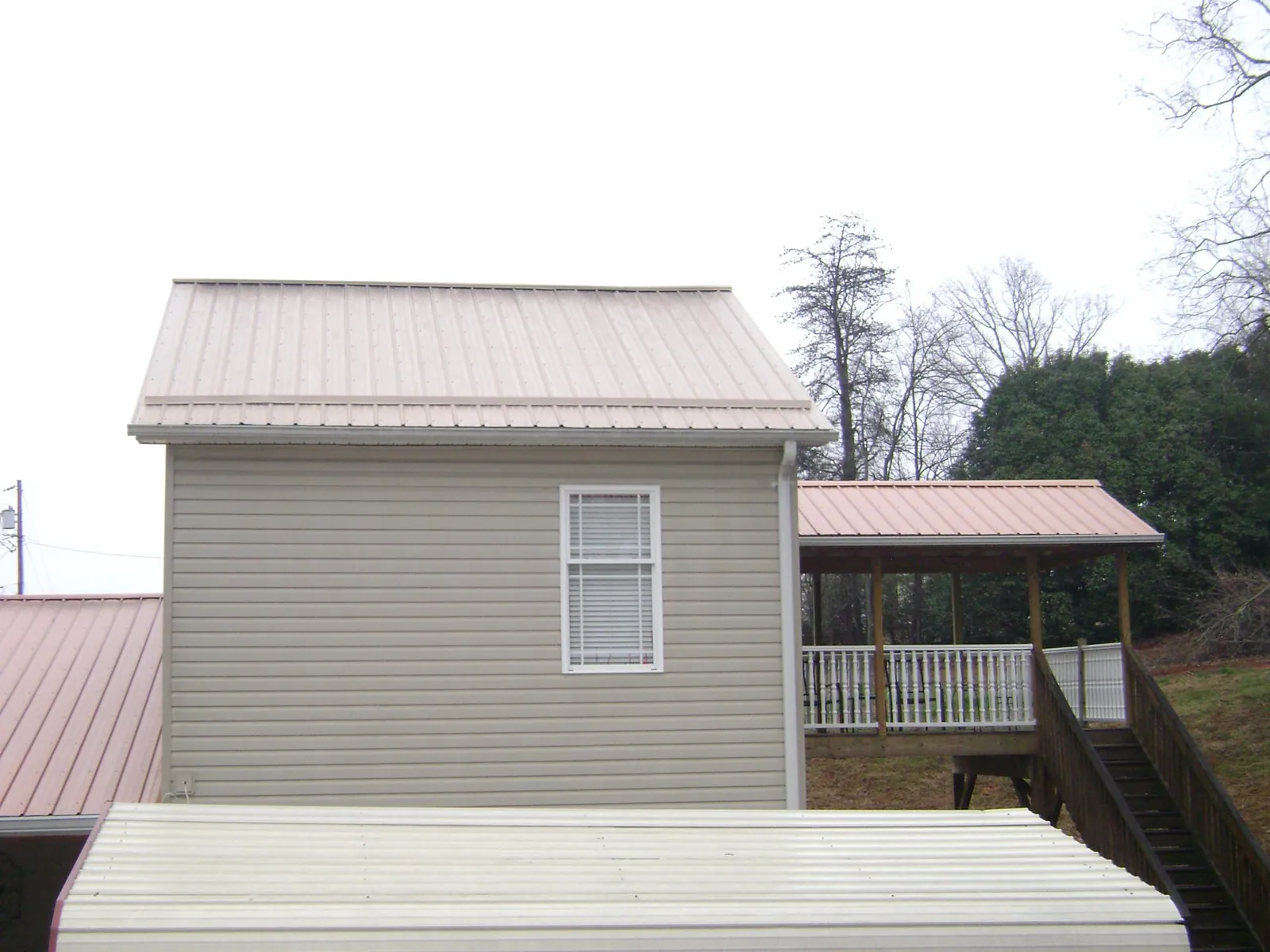 Tan metal roofs on a two story addition and attached porch, from a Roof Replacement job in Idleyld Park